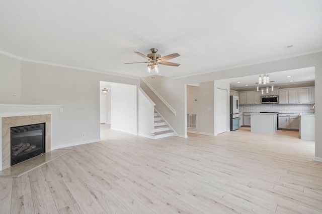 unfurnished living room featuring crown molding, ceiling fan, a high end fireplace, and light hardwood / wood-style flooring