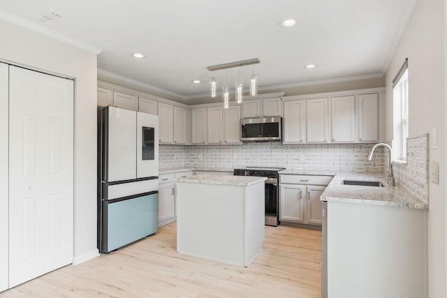 kitchen with sink, light hardwood / wood-style flooring, appliances with stainless steel finishes, a center island, and decorative light fixtures