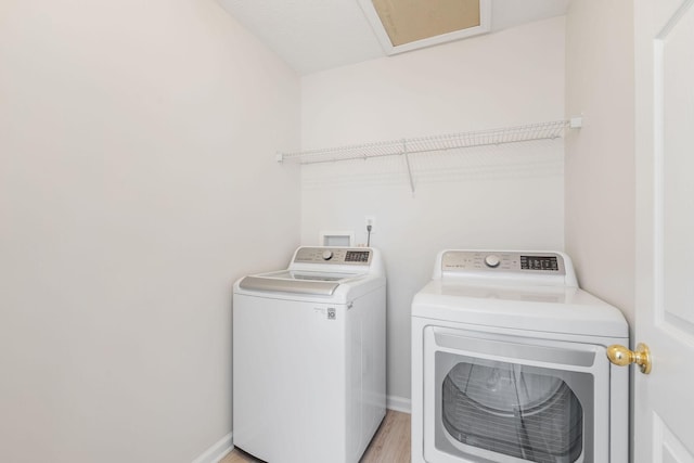 laundry room with independent washer and dryer and light wood-type flooring