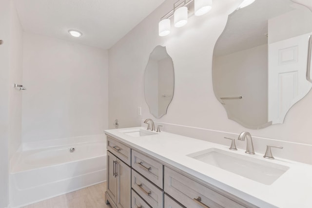 bathroom featuring hardwood / wood-style flooring, vanity, and a tub to relax in