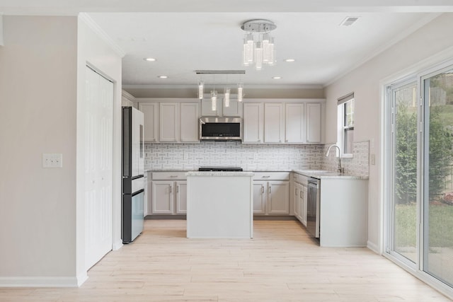 kitchen with appliances with stainless steel finishes, a center island, decorative backsplash, and decorative light fixtures