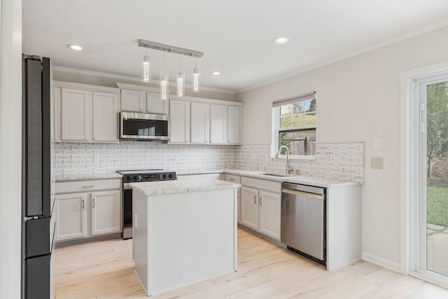 kitchen with sink, a center island, appliances with stainless steel finishes, pendant lighting, and backsplash