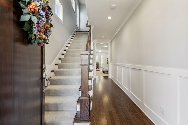 staircase with wood-type flooring and crown molding