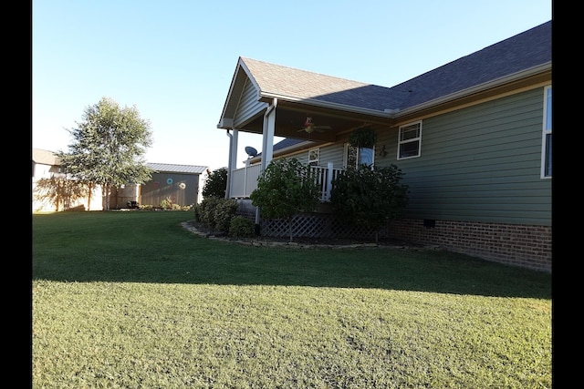 view of side of home featuring ceiling fan, a porch, and a lawn