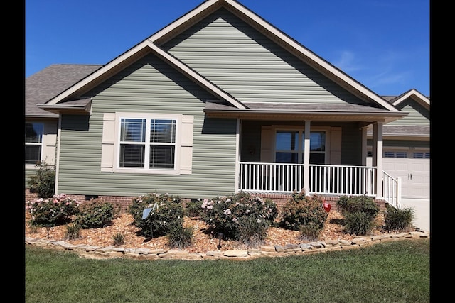 view of front of home featuring a porch, a garage, and a front yard