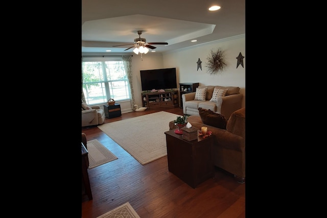 living room featuring dark wood-type flooring, ceiling fan, a tray ceiling, and crown molding