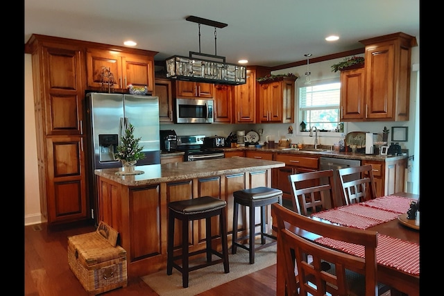 kitchen featuring dark hardwood / wood-style floors, decorative light fixtures, sink, dark stone counters, and stainless steel appliances