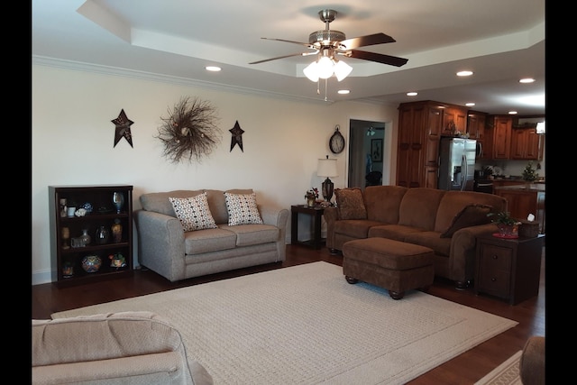 living room featuring dark wood-type flooring, ceiling fan, a tray ceiling, and crown molding