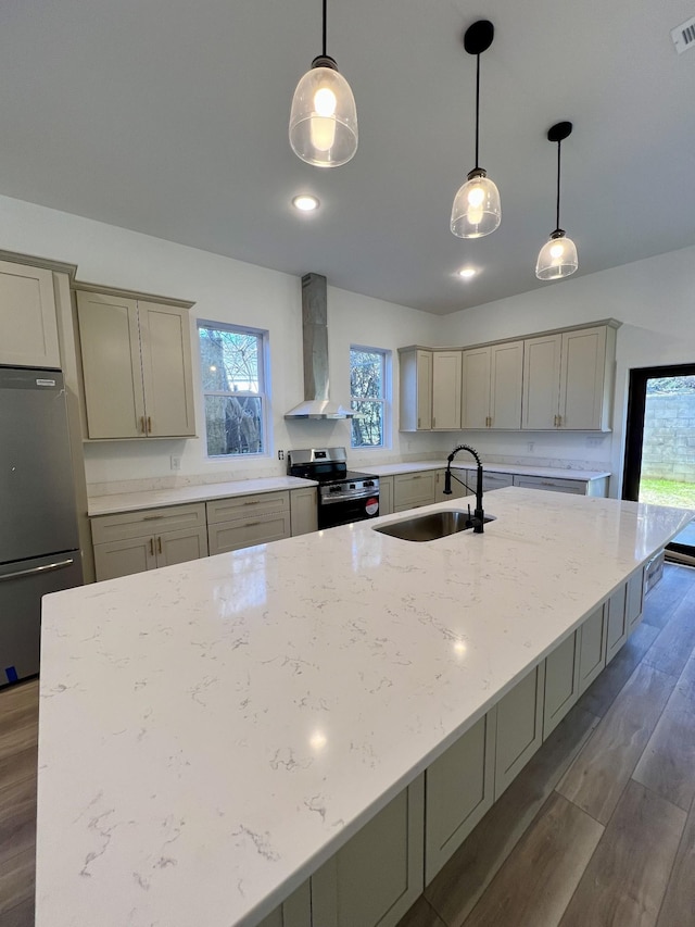 kitchen featuring wall chimney exhaust hood, sink, light stone counters, pendant lighting, and stainless steel appliances