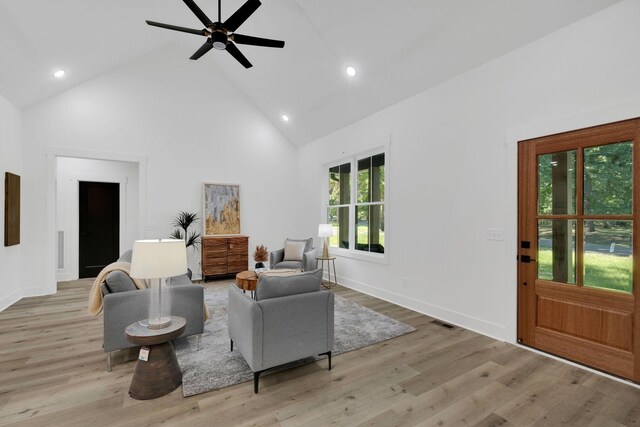 living room featuring ceiling fan, high vaulted ceiling, and light hardwood / wood-style flooring