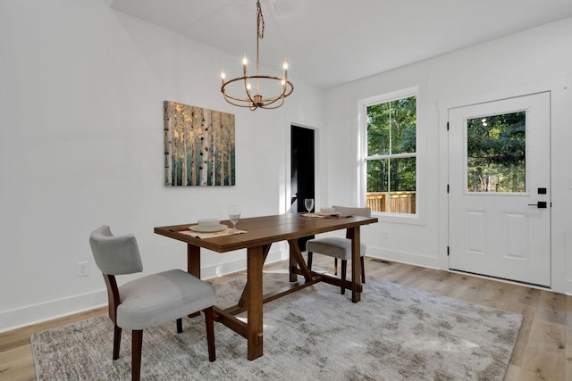 dining area with light hardwood / wood-style floors and a notable chandelier