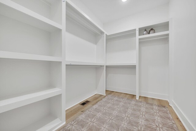 walk in closet with light hardwood / wood-style floors