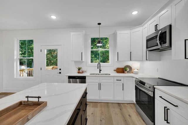 kitchen featuring white cabinetry, sink, decorative light fixtures, and stainless steel appliances