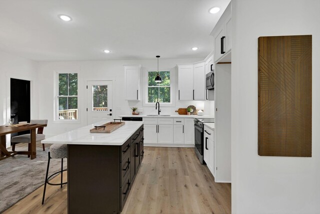 kitchen featuring sink, hanging light fixtures, appliances with stainless steel finishes, a kitchen island, and white cabinets