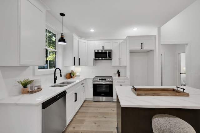 kitchen with sink, white cabinetry, light stone counters, hanging light fixtures, and appliances with stainless steel finishes