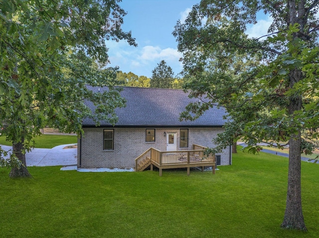 rear view of house featuring a wooden deck and a lawn