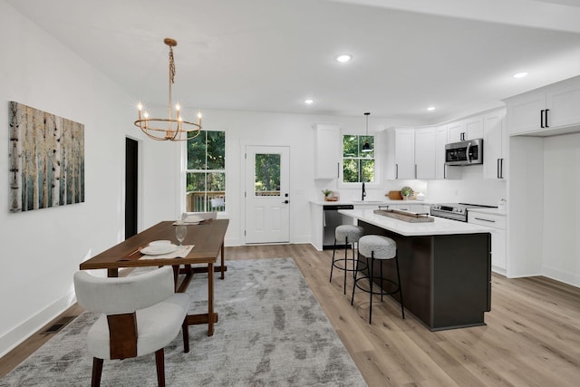 kitchen with white cabinetry, appliances with stainless steel finishes, decorative light fixtures, and a center island