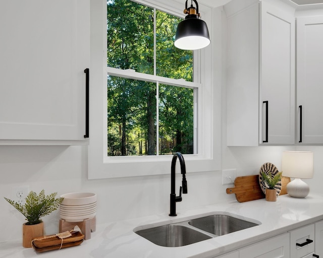 details featuring white cabinetry, sink, and light stone counters