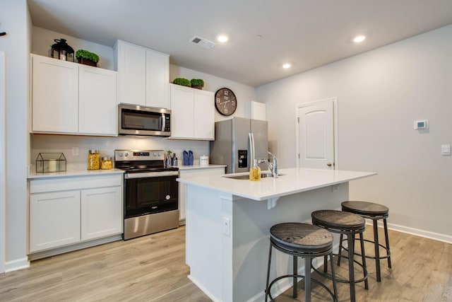 kitchen featuring a kitchen island with sink, sink, white cabinetry, and appliances with stainless steel finishes