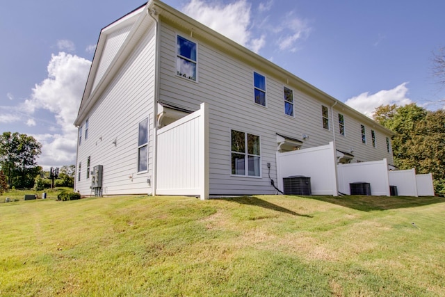 rear view of house featuring central AC and a lawn