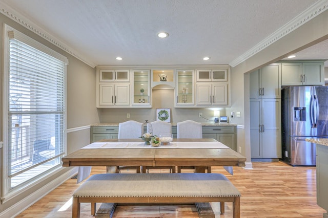 dining space with ornamental molding, light hardwood / wood-style floors, and a textured ceiling