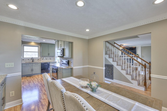 dining room with crown molding, light hardwood / wood-style floors, sink, and a textured ceiling