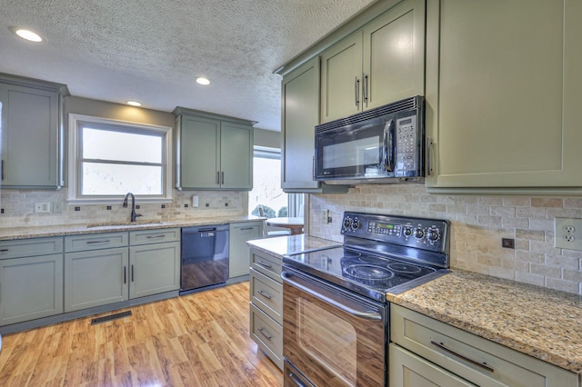 kitchen with sink, light hardwood / wood-style flooring, tasteful backsplash, black appliances, and light stone countertops