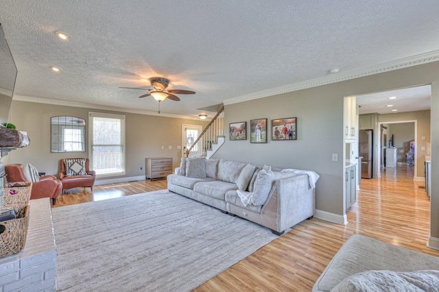 living room featuring ornamental molding, a textured ceiling, and light wood-type flooring