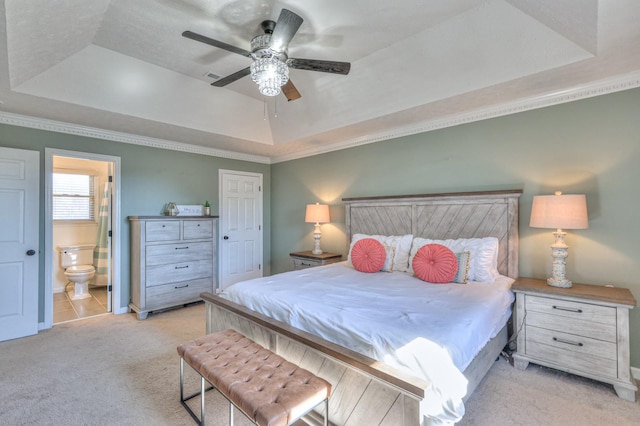 carpeted bedroom featuring ensuite bathroom, ceiling fan, and a tray ceiling