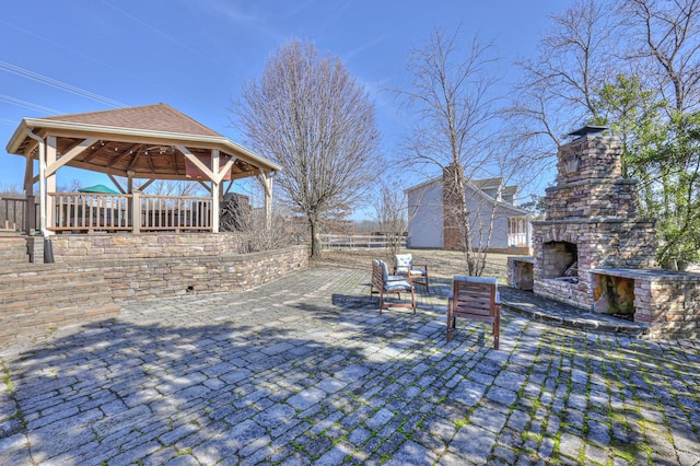 view of patio with a gazebo and an outdoor stone fireplace