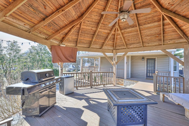 wooden terrace with a gazebo, ceiling fan, and an outdoor fire pit