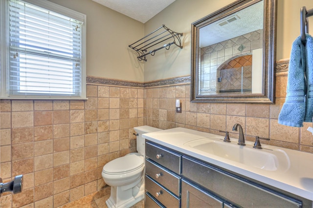 bathroom featuring vanity, tile walls, toilet, and a textured ceiling