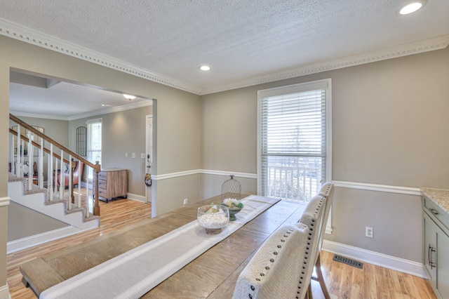 dining space featuring ornamental molding, a textured ceiling, and light hardwood / wood-style floors