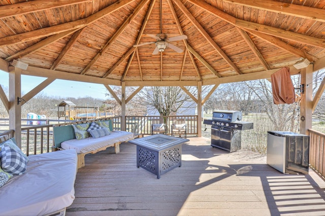 deck with a gazebo, area for grilling, ceiling fan, a playground, and an outdoor living space with a fire pit