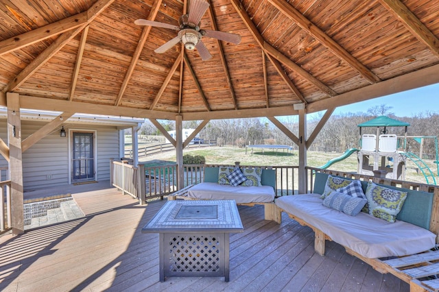 deck featuring ceiling fan, a gazebo, an outdoor living space with a fire pit, and a playground