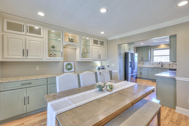 dining room featuring crown molding, sink, a textured ceiling, and light wood-type flooring