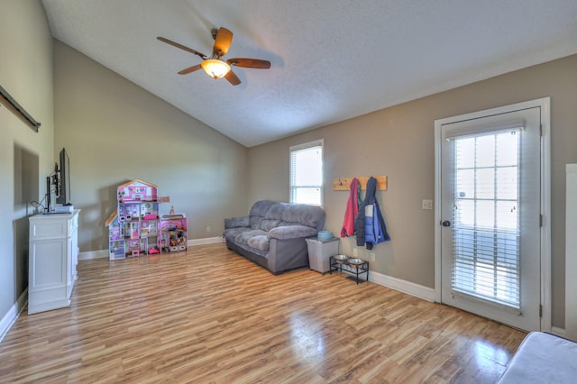 interior space featuring vaulted ceiling, ceiling fan, light hardwood / wood-style floors, and a textured ceiling