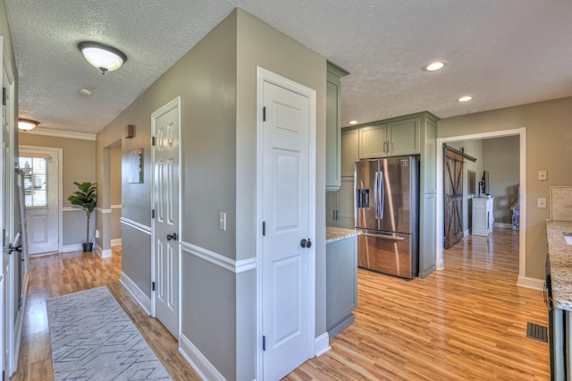 corridor featuring light hardwood / wood-style floors, a barn door, and a textured ceiling