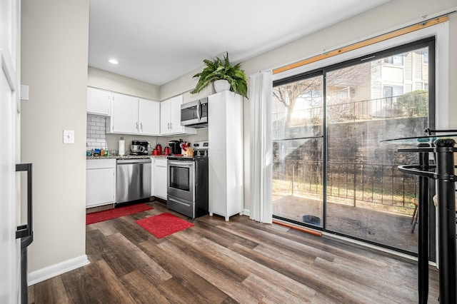 kitchen featuring dark hardwood / wood-style flooring, decorative backsplash, stainless steel appliances, and white cabinets