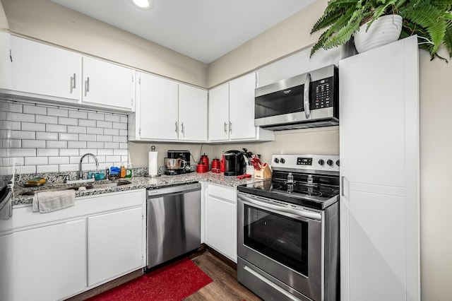 kitchen featuring dark wood-type flooring, white cabinetry, backsplash, stainless steel appliances, and light stone countertops