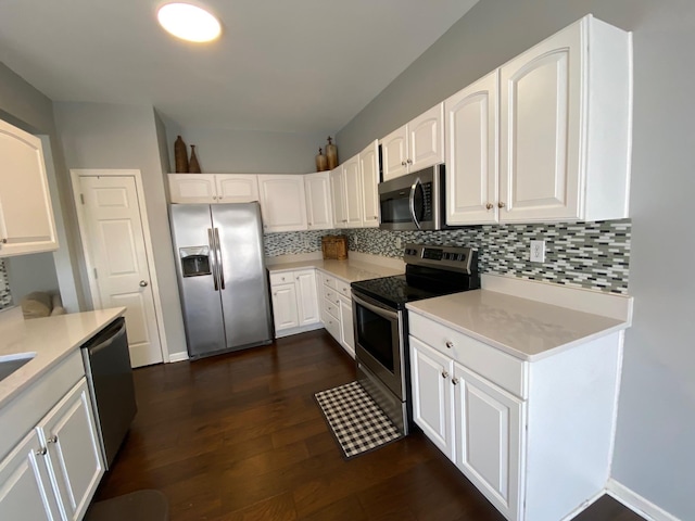 kitchen with appliances with stainless steel finishes, white cabinets, dark hardwood / wood-style flooring, and decorative backsplash