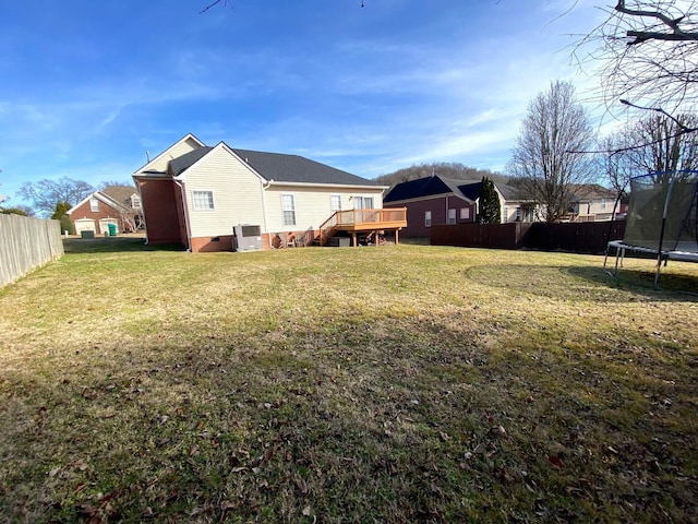 view of yard with a trampoline and a wooden deck