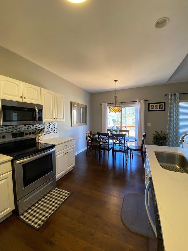 kitchen featuring sink, appliances with stainless steel finishes, white cabinetry, hanging light fixtures, and dark hardwood / wood-style floors