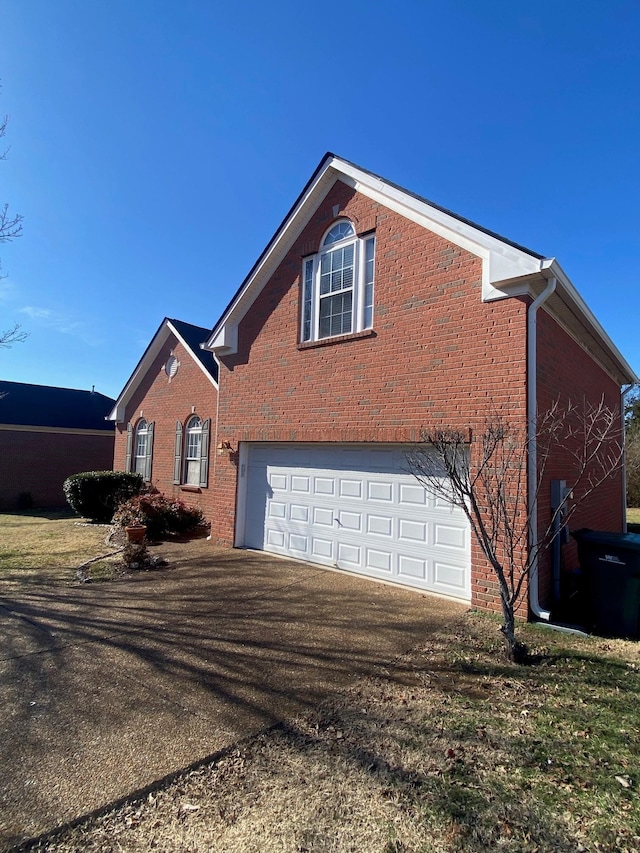 view of property exterior with brick siding, an attached garage, and aphalt driveway