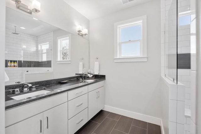 bathroom with tiled shower, vanity, and a wealth of natural light