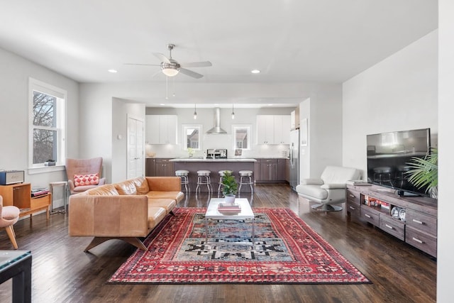 living room featuring ceiling fan and dark hardwood / wood-style floors