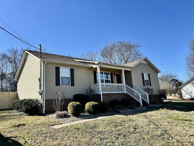 ranch-style house featuring covered porch and a front lawn