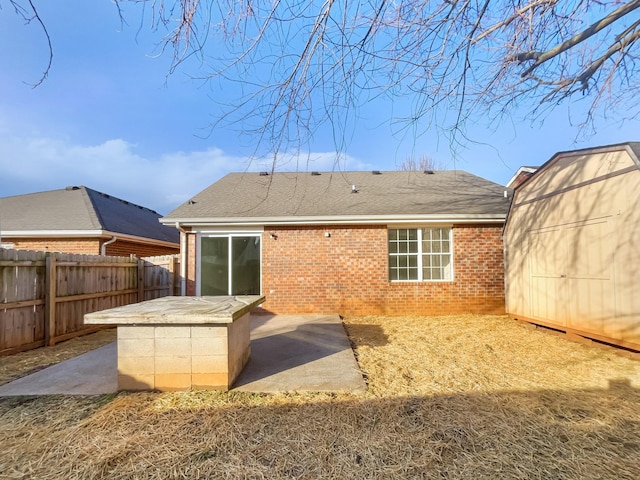 back of property with a shed and a patio