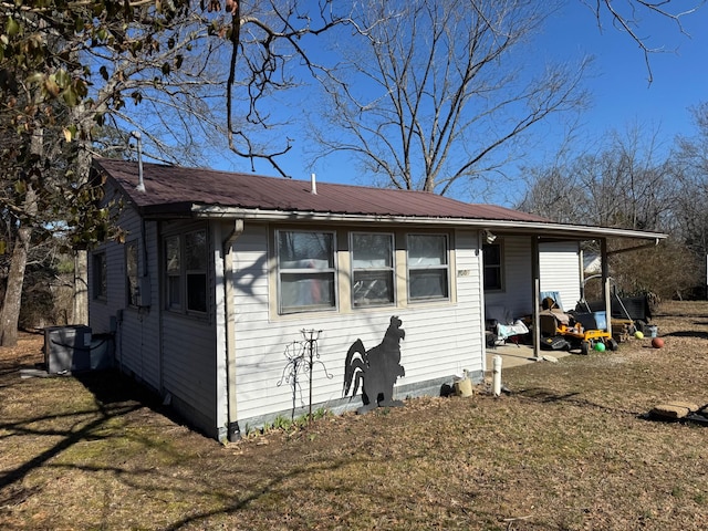 back of property featuring metal roof and a lawn
