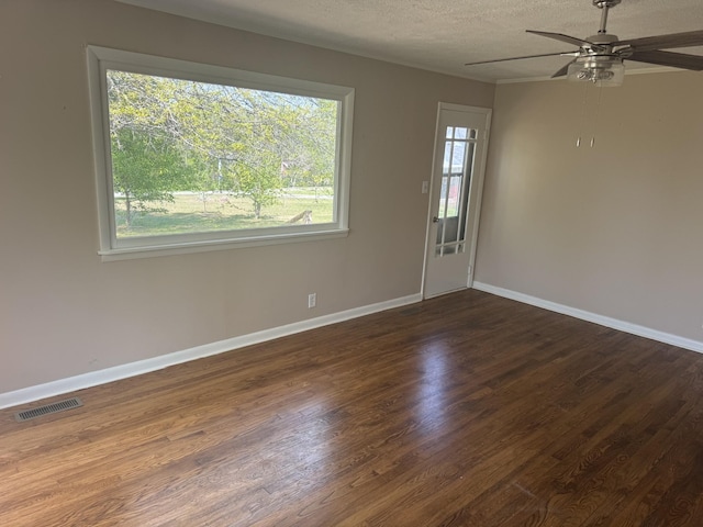 empty room featuring visible vents, baseboards, a ceiling fan, and dark wood-style floors
